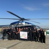 Hubschrauber auf Rollfeld. Davor steht das Team der Fliegerstaffel der Polizei NRW