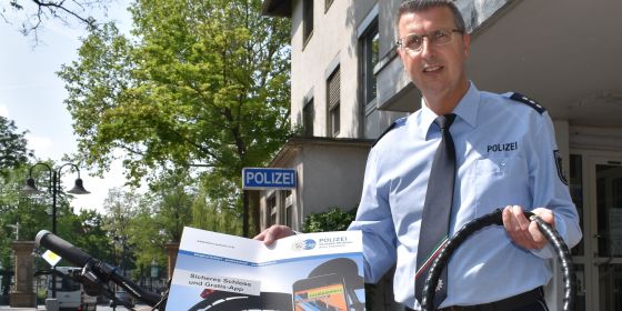 Peter Gall aus der Kriminalprävention der Kreispolizeibehörde Paderborn mit einem Fahrradschloss und einem Hinweis auf die Fahrradpass-App. 